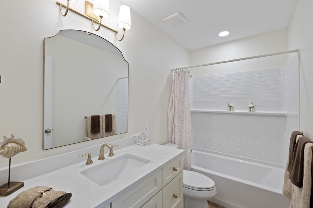 Bathroom with white vanity, arched mirror and tub