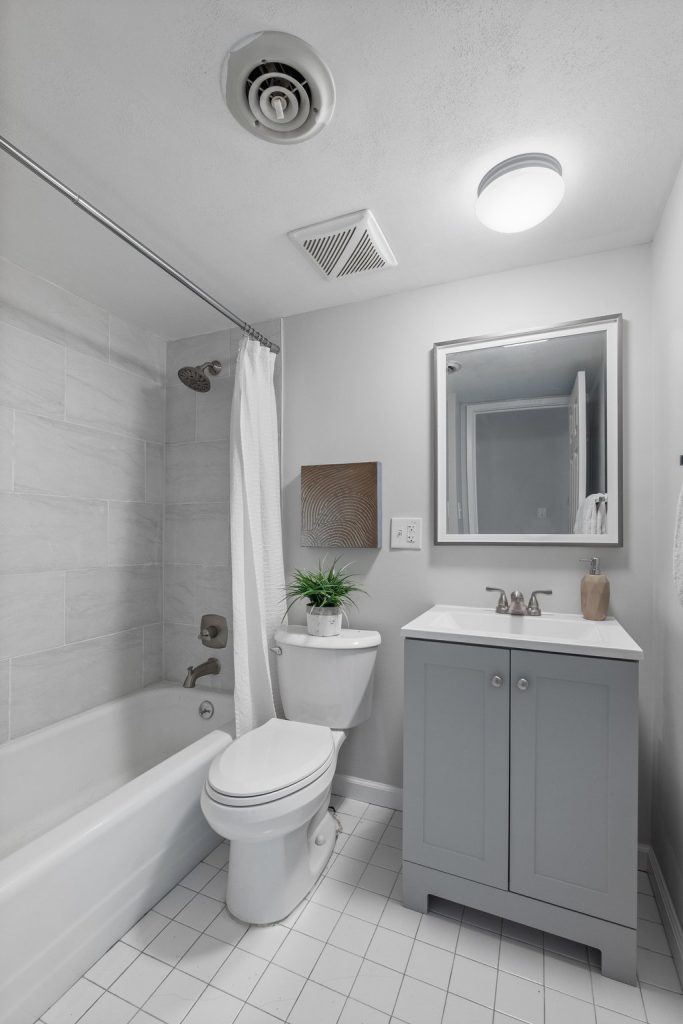 Bathroom with gray vanity and tiled tub surround